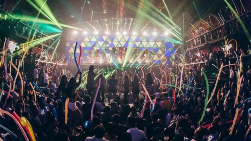 A crowded indoor event with a stage and colorful lighting. 2