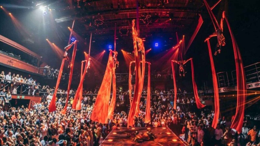 A circus performance with acrobats performing on high poles and a large crowd watching. 1