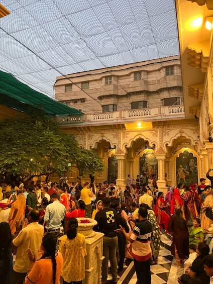 A crowded courtyard with people gathered around a central area, possibly for a cultural or religious event. 1