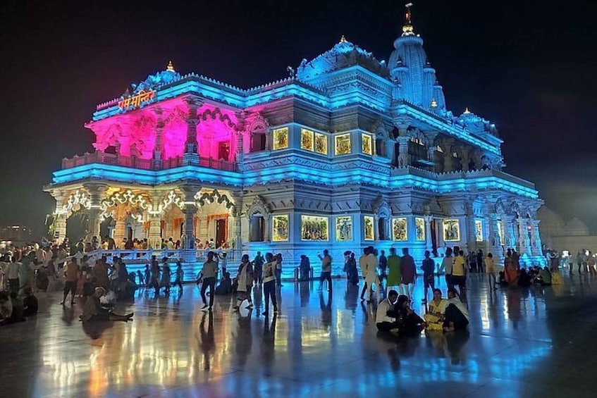 A brightly lit temple with intricate architecture and a large crowd gathered around it. 2