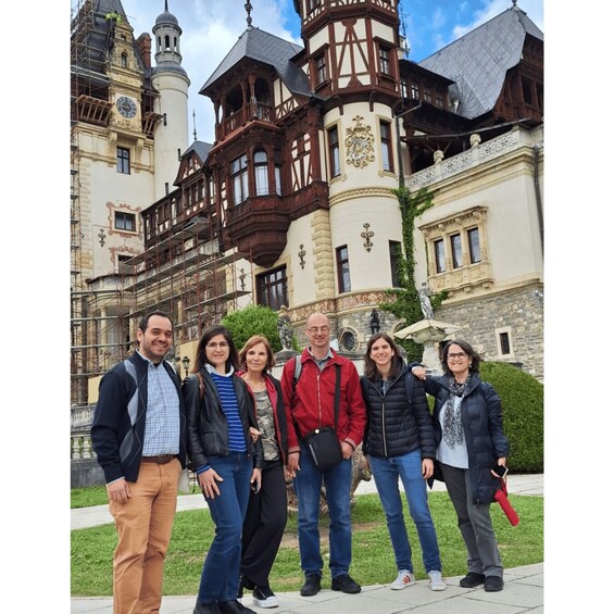 A group of people standing in front of a historic building with a clock tower and ornate architecture. 3