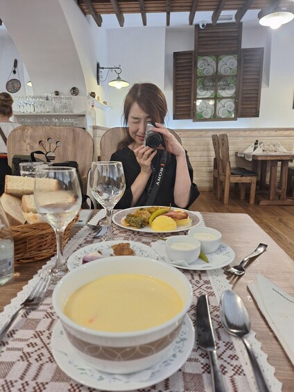 A person taking a photo with a camera at a dining table with food and drinks. 5