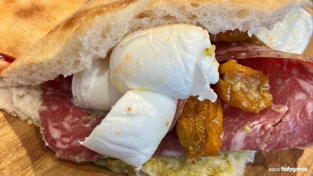 A sandwich with bread, mozzarella, salami, and a green sauce. 1