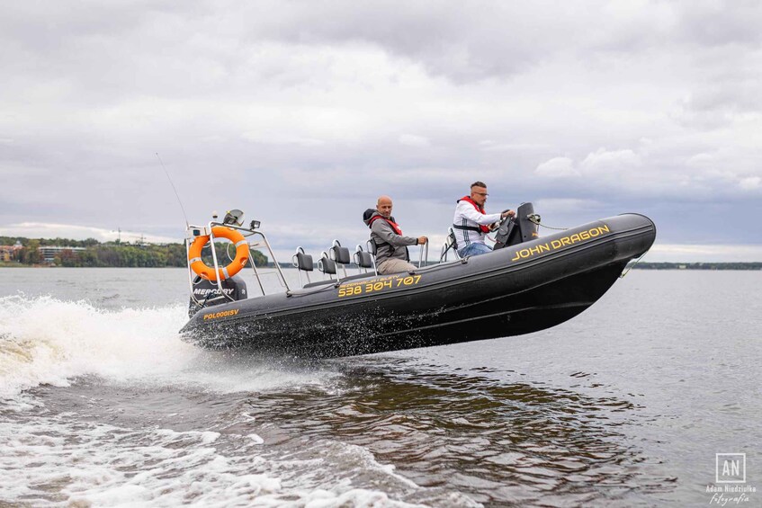 Two people jet-skiing on a black boat with 'John Dragon' written on the side. 5
