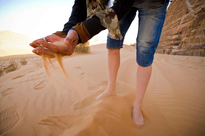 A person standing in a desert with sand dunes in the background. 1