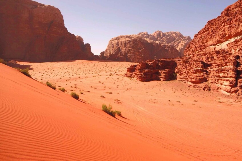 A desert landscape with red sand dunes and rocky formations. 4