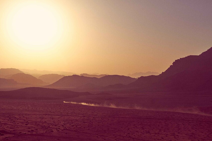 A desert landscape with mountains in the background and a body of water in the foreground. 3