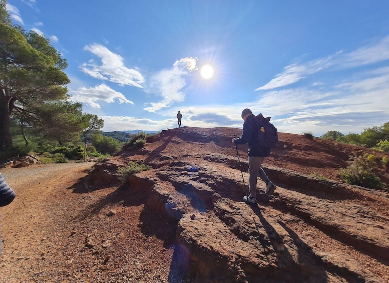 Two hikers on a rocky trail with a clear sky and sun. 5