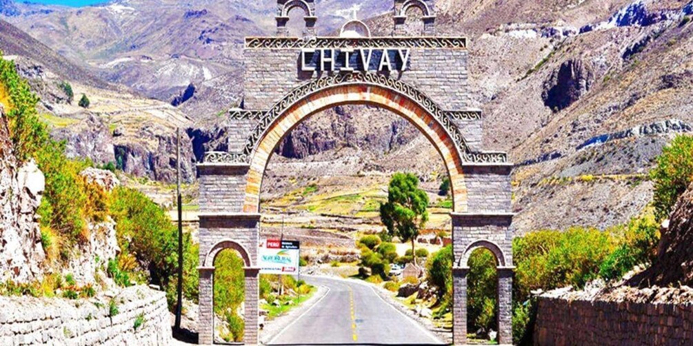 A stone archway with 'CHILVA' inscribed above a road leading through a mountainous landscape. 4
