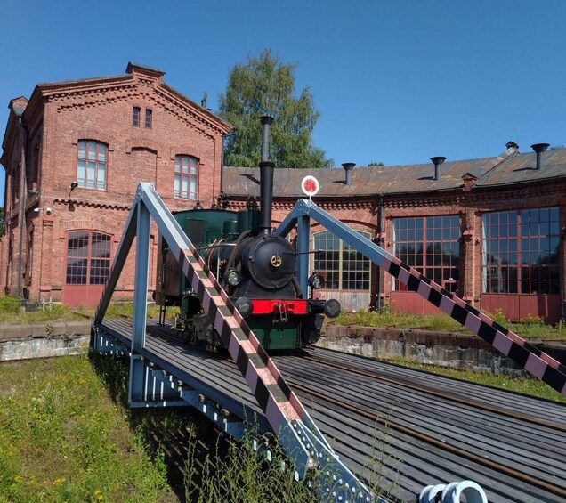 A steam locomotive on a railway track with a bridge overhead. 5