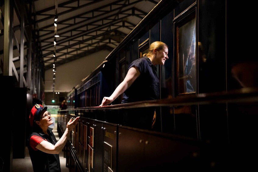 A person reaching out from a train car to another person standing outside. 3
