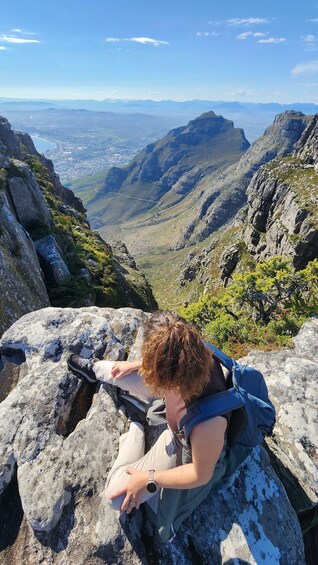 A person sitting on a rock with a backpack, overlooking a mountainous landscape. 4