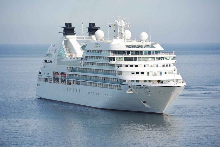 A large white cruise ship with multiple decks and a funnel, sailing on calm waters. 5