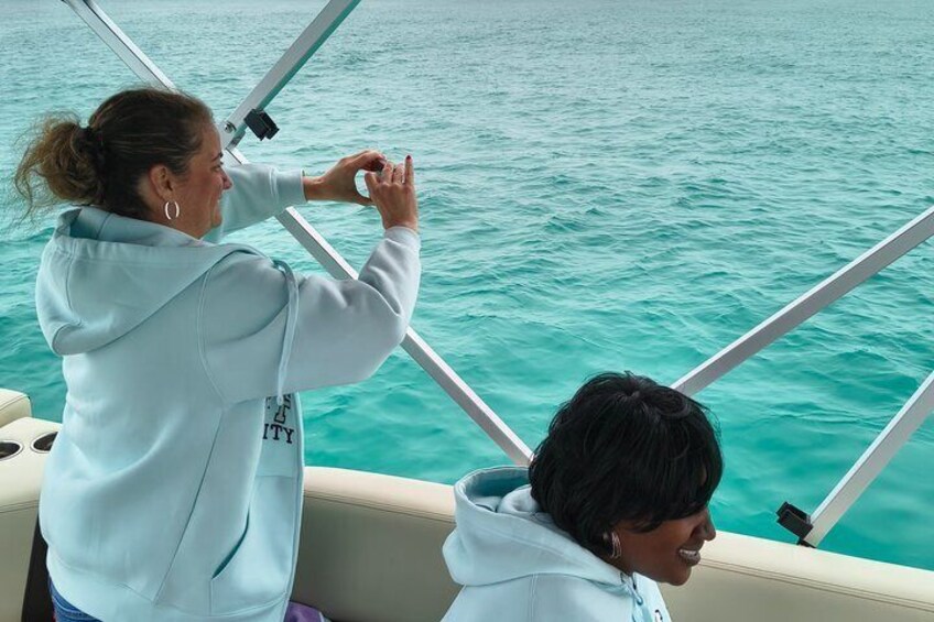 A person in a light blue hoodie steering a boat on turquoise water. 5