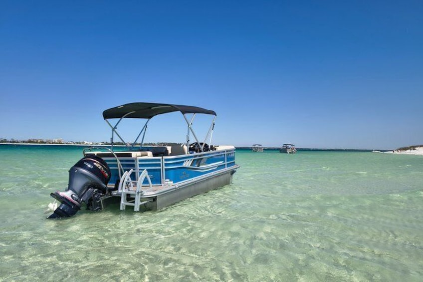 A boat with a motor and canopy, anchored in clear turquoise water. 3