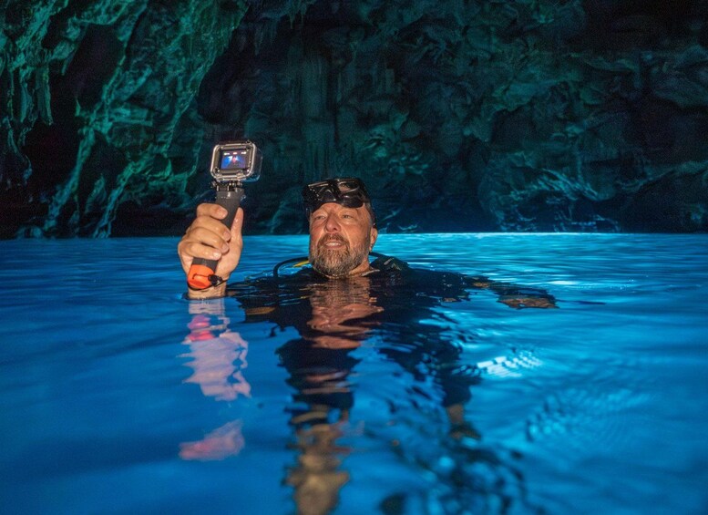 A person in a swimming pool with a camera, wearing goggles, and a wetsuit. 2