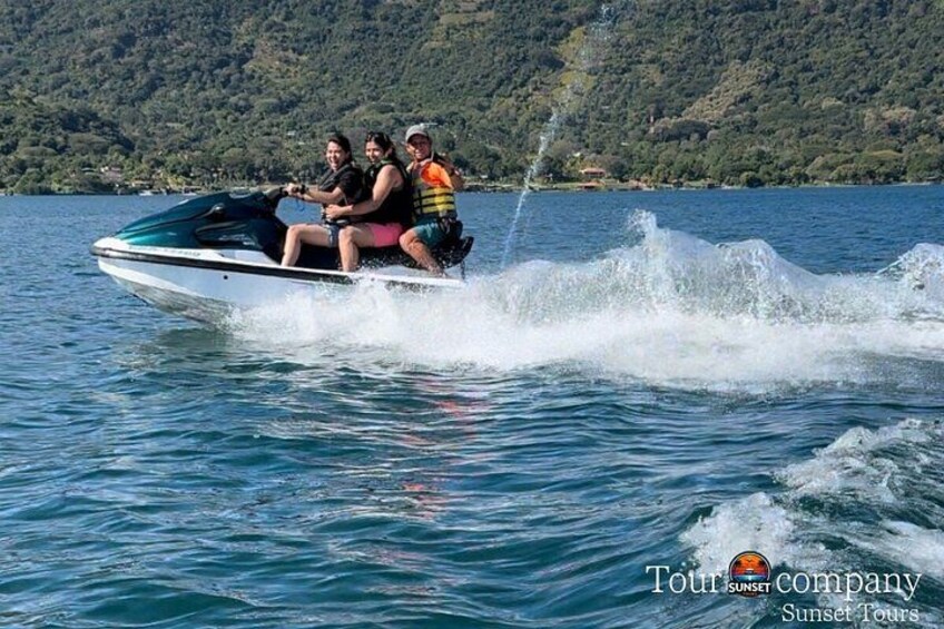 A watercraft with three people on it, moving across a body of water with a mountainous landscape in the background. 4