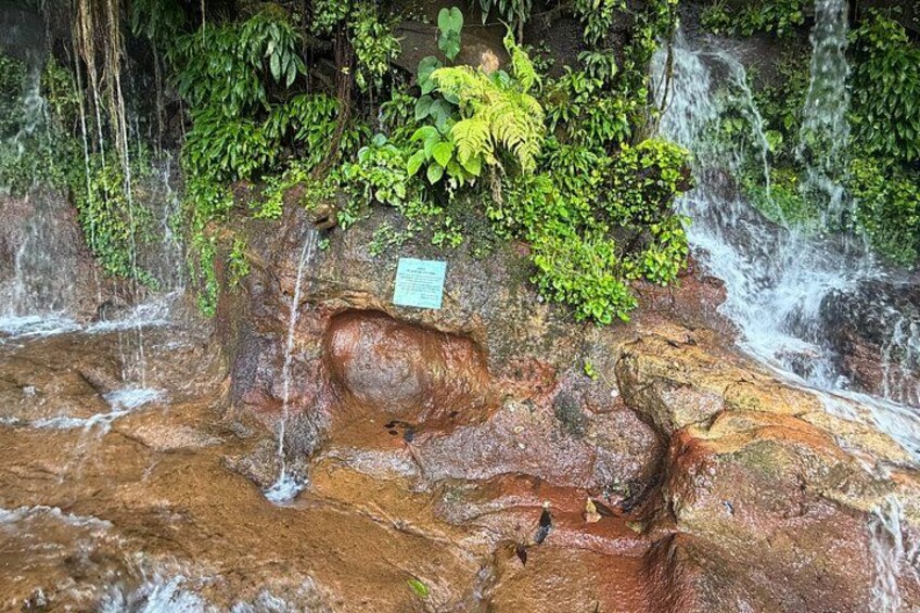 A natural waterfall with water flowing over rocks and lush greenery. 3