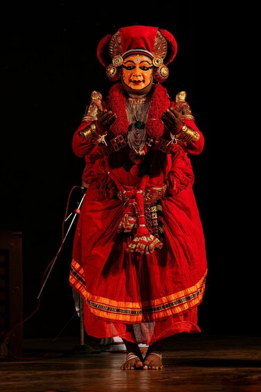 A person in a red costume with gold accents, holding a staff. 5