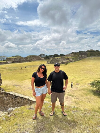 A couple standing on a grassy field with ancient ruins in the background. 4