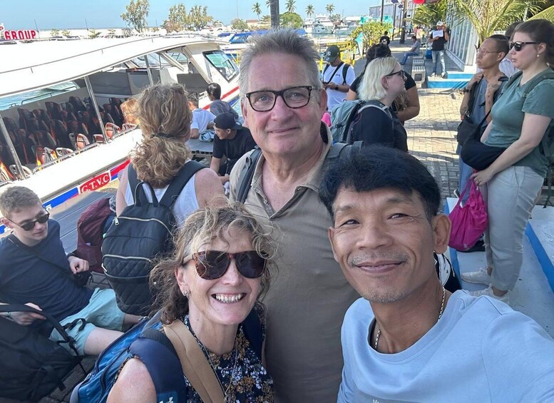 A group of people on a boat with a 'GROUP' sign, a cityscape with palm trees, and a clear sky. 5