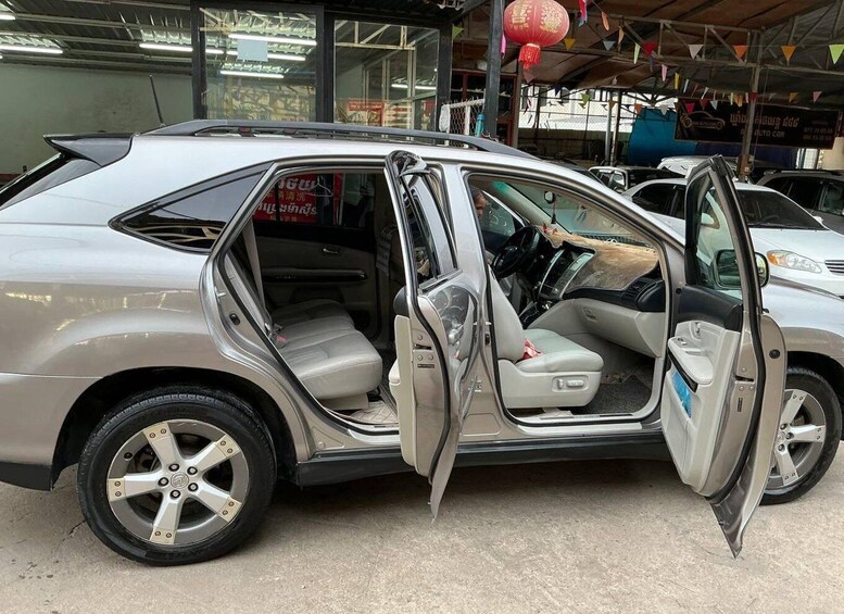 A silver car with its doors open, parked in a garage with other vehicles. 3