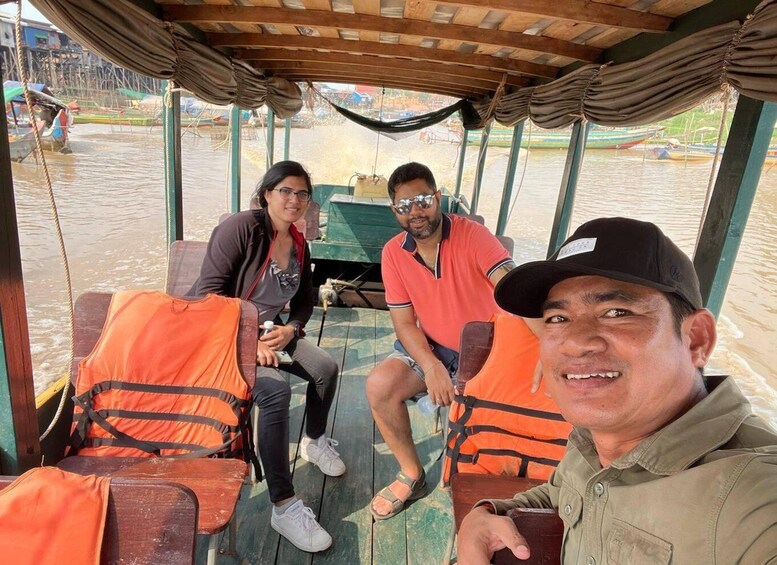 Three people on a boat with life jackets and a covered deck. 4