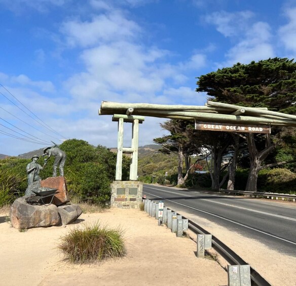 A road sign for Great Ocean Road, a statue of a man with a shovel, and a wooden structure. 5