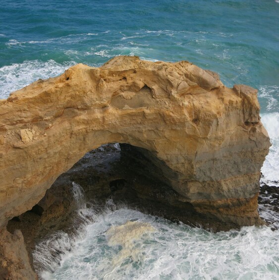 A natural rock arch formation with waves crashing through its opening. 3