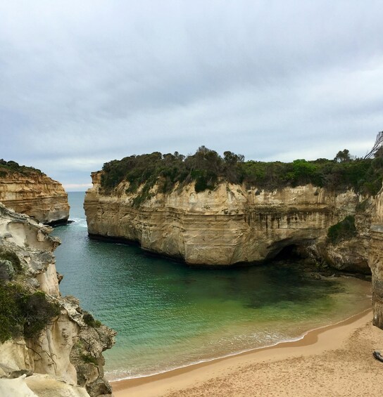 A coastal landscape with cliffs, a beach, and calm sea. 2