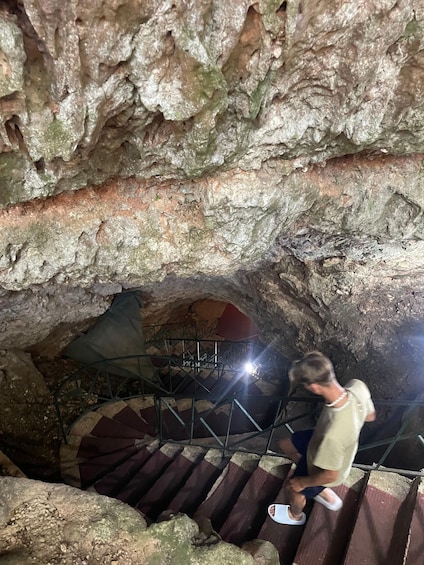 A person descending a metal staircase in a cave with rocky walls. 5