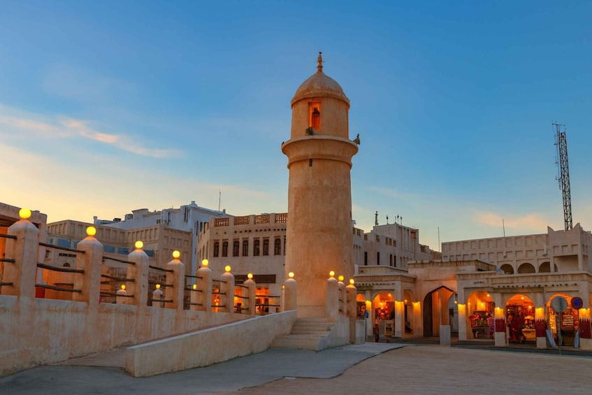 A historic tower with a dome, surrounded by traditional buildings and a pedestrian bridge with lights. 1