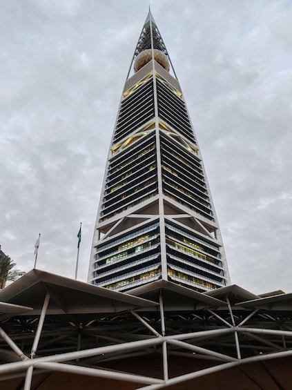 Un rascacielos alto y moderno con una parte superior triangular distintiva y fachada con diseño de cuadrícula. 3