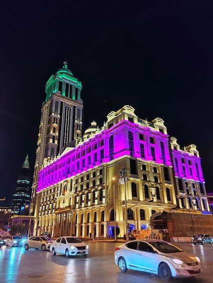 Un edificio muy iluminado con una torre y una fachada iluminada en verde y morado. 5