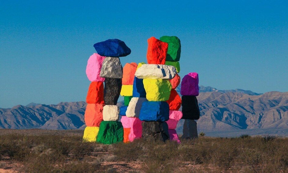 Colorful rock formations in a desert landscape with mountains in the background. 1