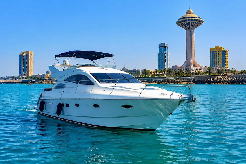 A white yacht on calm turquoise waters with a city skyline and a distinctive tower in the background. 2