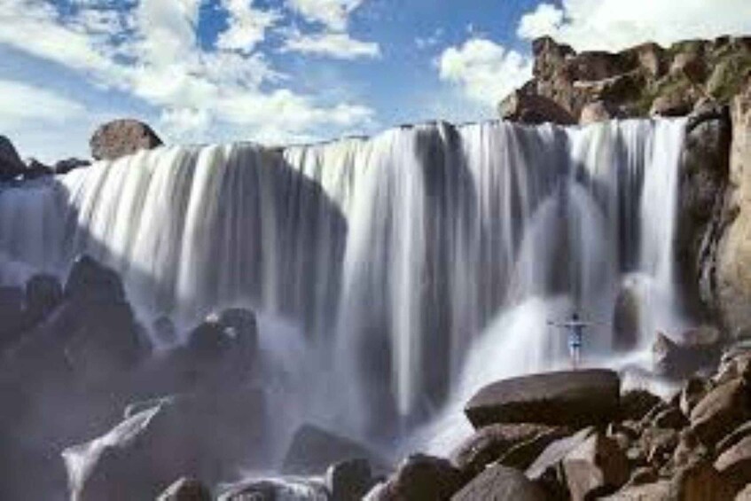 Een waterval die over rotsen stroomt, met een heldere lucht erboven. 3