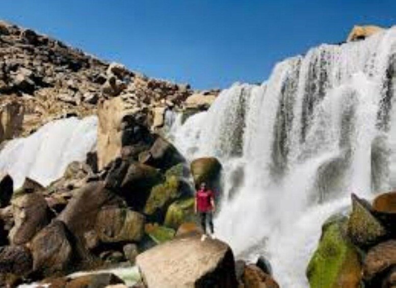 Een waterval met een persoon ervoor staand. 1