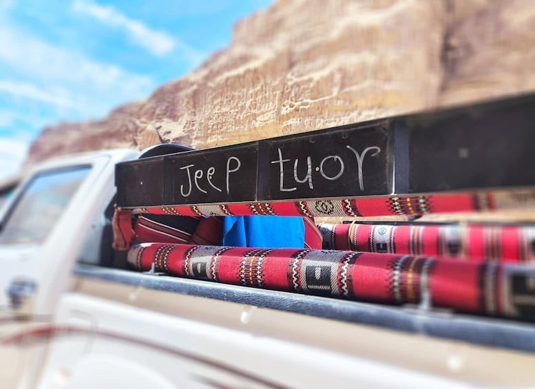 A Jeep parked with a bedload of colorful blankets and a sign that reads "Jeep tuor". 4