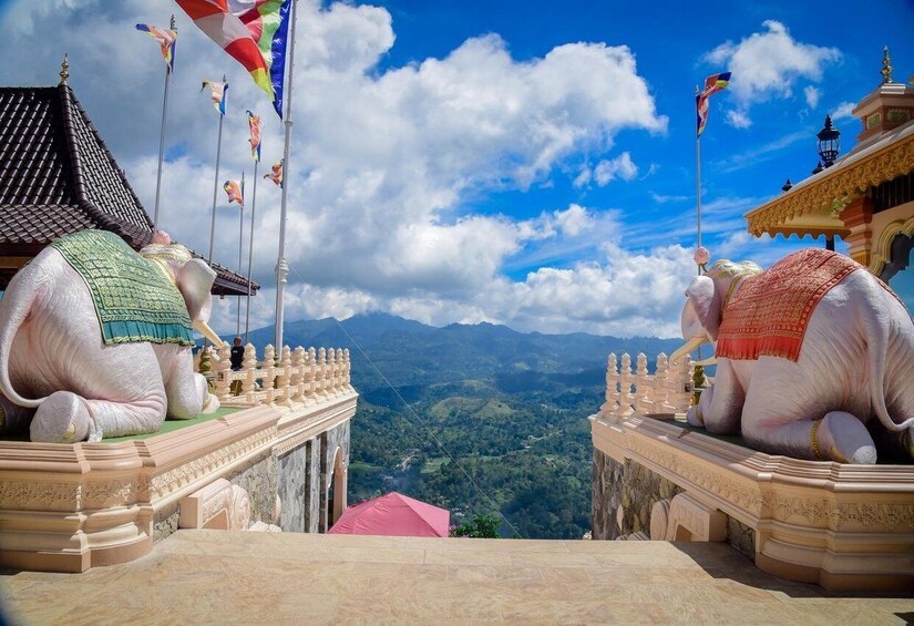 Two large elephant statues on a viewing platform overlooking a mountainous landscape. 1