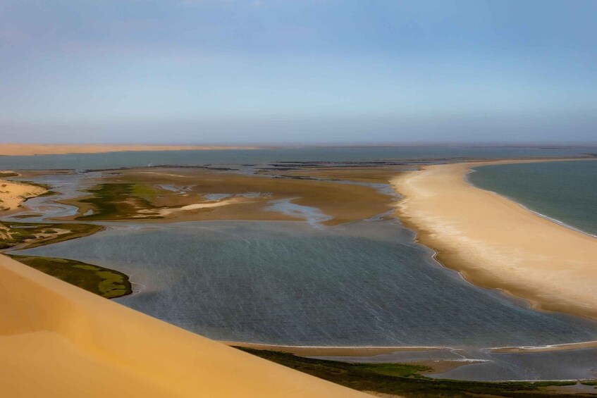 A coastal landscape with a sandy beach, calm waters, and a distant horizon. 5