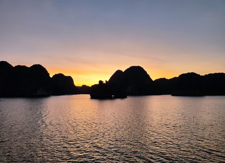 A calm body of water with a boat in the center, surrounded by rocky formations during sunset. 1