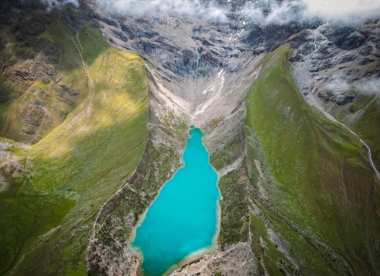 Un lago turchese circondato da colline verdi e terreno roccioso. 3