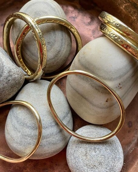 A collection of gold rings on a bed of smooth, rounded stones. 1