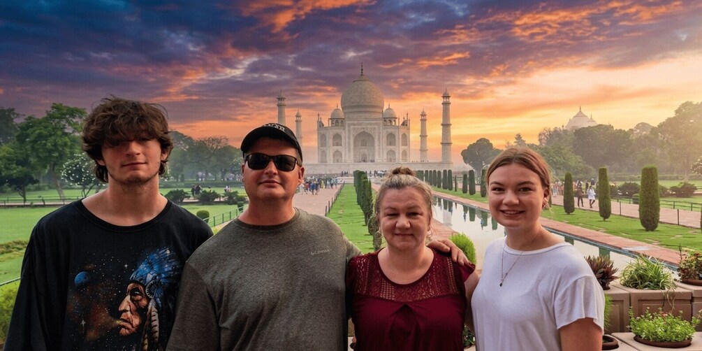 Un groupe de personnes se tient devant le Taj Mahal, avec un coucher de soleil en arrière-plan. 1