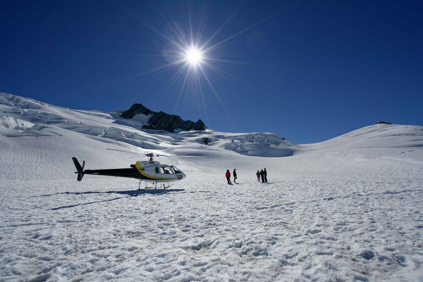 A helicopter on a snowy mountain with a bright sun in the background. 2