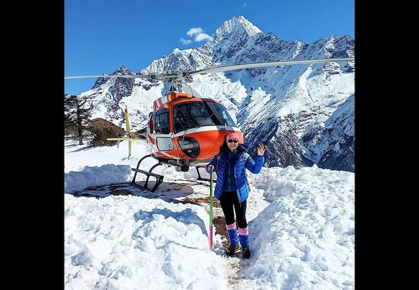 A person standing in snow with a helicopter in the background. 3