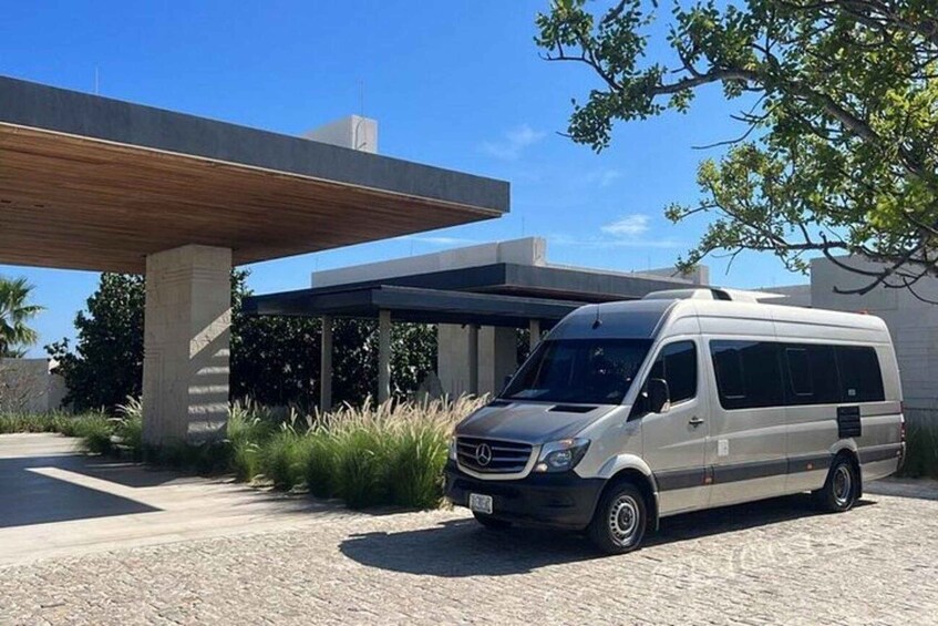 A Mercedes van parked in front of a modern building with a covered walkway. 1