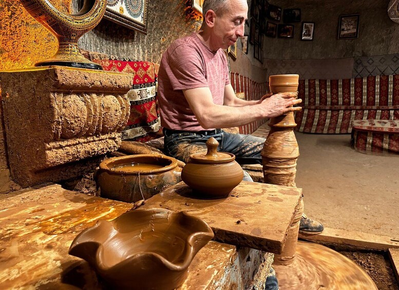 A person shaping a clay pot on a pottery wheel in a workshop. 1