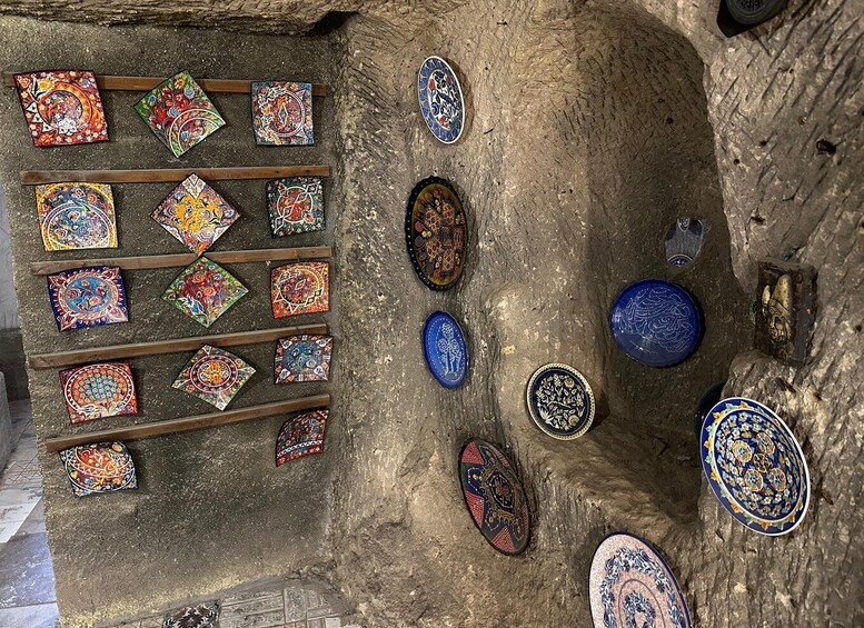A collection of colorful, intricately designed tiles and plates arranged on a stone surface. 3